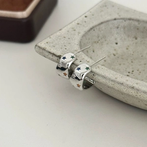 Detail of silver star earrings featuring colorful zircon stones on a stone tray