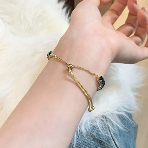 Adjustable gold box chain bracelet with navy blue square gemstones on a model's wrist