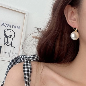 French retro style large white pearl earrings with gold hooks worn by a model