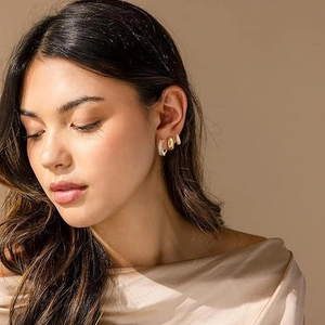 Ensemble de boucles d'oreilles dorées avec zircons brillants porté par un mannequin