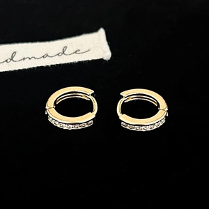 Vue macro de boucles d'oreilles huggies dorées avec cristaux sur velours noir