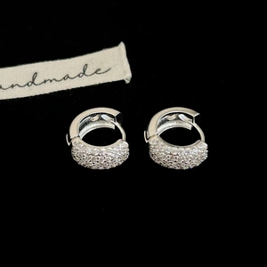 Vue macro de boucles d'oreilles huggie en argent avec zircons micro-pavés sur fond noir