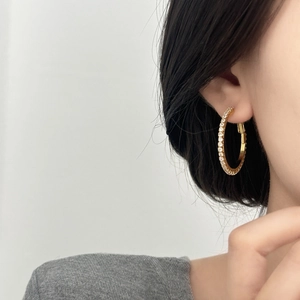 Créoles dorées élégantes avec pavé de zircons vues de profil sur un mannequin
