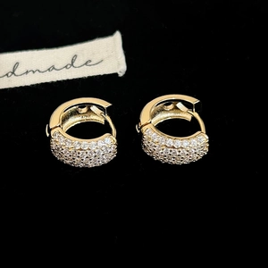 Vue macro des boucles d'oreilles créoles dorées avec pavé de zircone sur velours noir