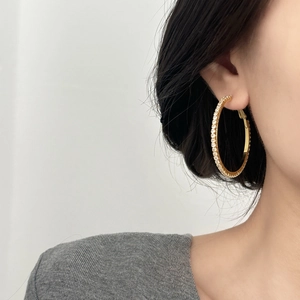 Grandes boucles d'oreilles créoles dorées serties de zircons brillants sur mannequin