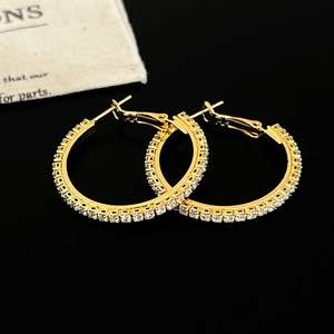 Gros plan de boucles d'oreilles créoles dorées avec zircons sur fond noir réfléchissant