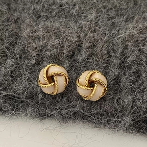 Boucles d'oreilles nœud tressé doré avec émail blanc sur fond en laine grise