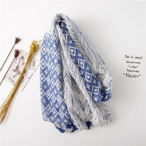 Détail du châle à imprimé plumes bleu et blanc avec pompons et perles en bois