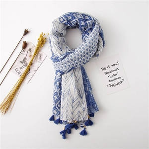 Détail de l'écharpe géométrique bleue et blanche avec pompons et perles dorées