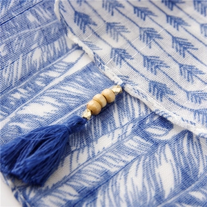 Détail du foulard bohème avec imprimé plumes bleu et blanc et pompons en perles de bois