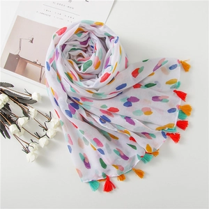 Artistic detail of colorful polka dot scarf with vibrant tassels on a soft fabric
