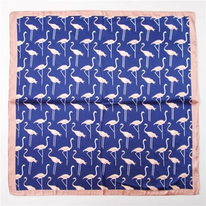 Détail d'un foulard en soie bleu marine avec motifs flamants roses et bordures