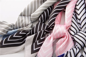 Détail de foulards en satin de soie avec rayures géométriques et motifs à chevrons