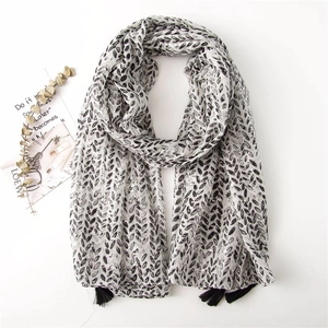 Detail view of cotton linen scarf with black leaf print and delicate fringe accents