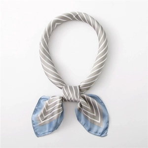 Détail d'un foulard en soie à rayures grises et bordure bleue noué autour du cou
