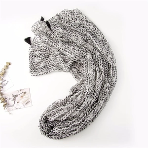 Detail of white cotton linen scarf with black leaf print and tassels on edges
