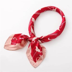 Détail d'un foulard en satin rouge avec imprimé flamant rose et texture soie