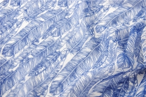 Texture détaillée d'une écharpe légère en coton avec motif plumes bleues sur fond blanc