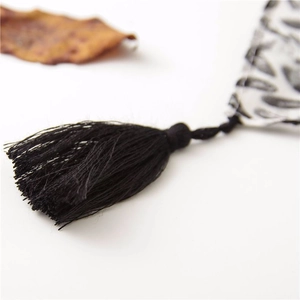 Close-up of black tassels and elegant monochrome floral pattern on a cotton linen scarf