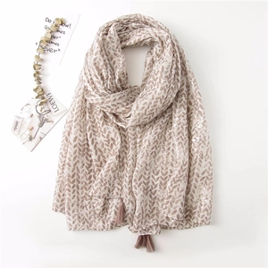 Detailed macro of a beige cotton linen shawl featuring a light brown leaf pattern and tassels