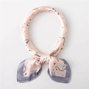 Gros plan du foulard en soie rose avec motifs de flamants roses et bordure grise