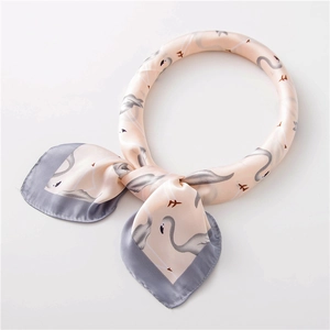 Détail d'un foulard carré en soie rose et gris avec motifs flamants roses et oiseaux