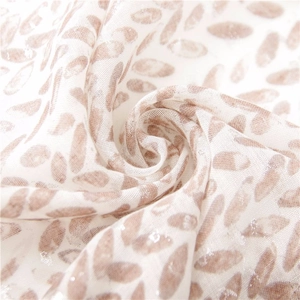 Detail of soft linen scarf featuring abstract leaf patterns and subtle silver glitter accents