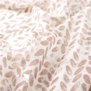 Close-up of cotton linen scarf featuring leaf patterns and shimmering silver sequins