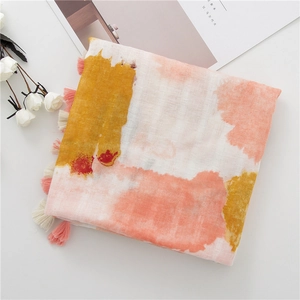 Détail d'une écharpe en coton et lin avec imprimé aquarelle orange et bordures à franges