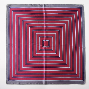 Détail d'un foulard carré en soie aux motifs géométriques rouge foncé et bleu marine