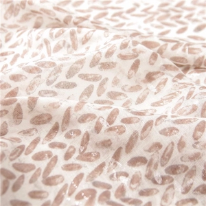 Detail of soft cotton linen scarf showing light coffee oval patterns and fringe texture