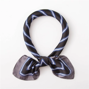 Détail d'un foulard en soie carré avec motifs géométriques en V bleus et blancs sur noir