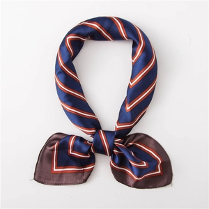 Détail d'un foulard en soie noué avec des rayures bleu marine, orange et blanches