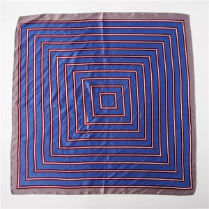 Détail d'un foulard carré en soie avec motifs géométriques bleu marine et rouges