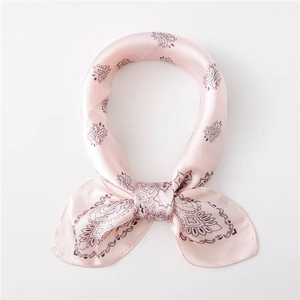 Detailed close-up of light pink paisley silk scarf with satin texture and clean edges