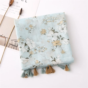 Detail of light blue floral cotton linen scarf featuring soft tassels and fringe edges