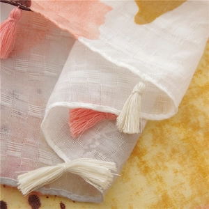 Détail du tissu d'une écharpe en dégradé avec glands roses et texture quadrillée