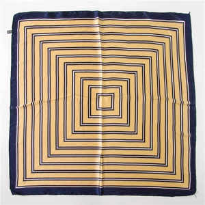 Détail d'un grand foulard en soie au motif géométrique bleu marine et doré avec texture satin