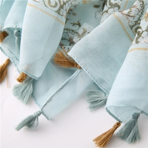 Detailed macro view of light blue floral cotton scarf with intricate fringe tassels
