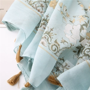 Close-up of blue floral print linen scarf featuring delicate fringe and retro patterns