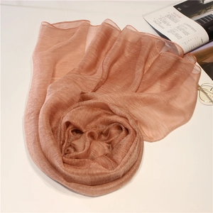 Détail d'une écharpe en soie et laine plissée or rose avec un éclat métallique chic