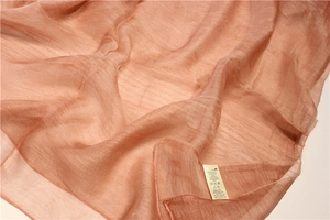 Détail macro d'une écharpe en soie et laine rose corail avec texture et étiquette