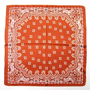 Close-up of orange paisley silk scarf with geometric floral patterns on white background
