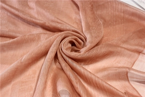 Détail macro d'une écharpe en soie rose doré avec lustre métallique et texture sergé