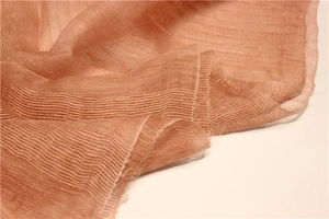 Détail macro du tissu en soie et laine rose terre cuite avec texture plissée élégante