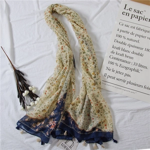 Detailed close-up of floral cotton linen scarf with blue borders and white tassels