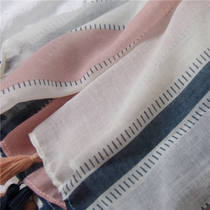 Detailed view of striped cotton linen scarf with soft fringe and light fabric texture