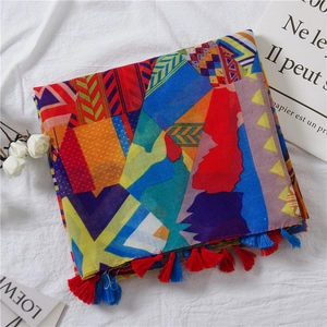 Détail d'une écharpe à imprimé géométrique coloré avec franges sur fond blanc texturé