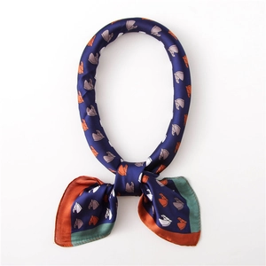 Detail of silk satin scarf featuring navy horse print and orange contrasting borders