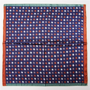 Close-up of square satin scarf with navy blue horse print and orange color-block edges